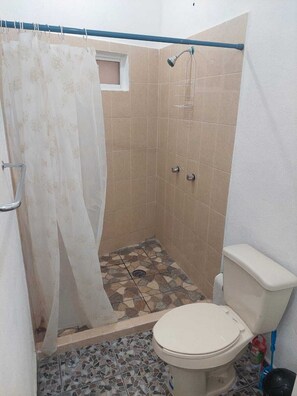 Kylpyhuone, jossa on suihku, wc ja laatoitettu lattia.