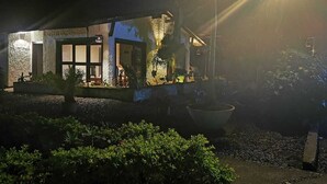 A building with a stone facade, large windows, and a well-lit entrance area with a planter and pathway. - Cabaña Colonia Española (Risaralda)