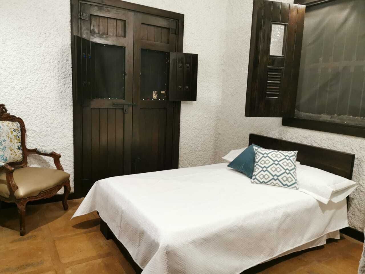 Ein Schlafzimmer mit einem Bett, einem Sessel und einer Holztür.