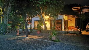 A building with a gravel driveway, potted plants, and a wooden bench. - Cabaña Colonia Española (Risaralda)