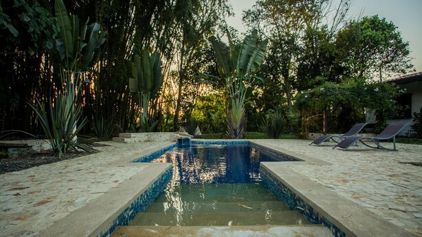 A rectangular swimming pool with a tiled edge, surrounded by a stone patio. - Cabaña Colonia Española (Risaralda)