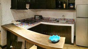A kitchen with a curved countertop, a built-in sink, and dark cabinetry. - Cabaña Colonia Española (Risaralda)