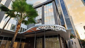 A modern hotel with a curved facade, large windows, and a palm tree in front. - AC Hotel by Marriott Honolulu (Honolulu)
