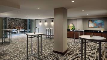 Un moderno hall de hotel con mesas redondas, una pared de piedra y una obra de arte contemporánea.