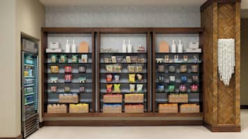 Eine Snackbar mit Regalen voller verschiedener verpackter Snacks und Getränke, einer Kühlvitrine und einer dekorativen Wandverkleidung.