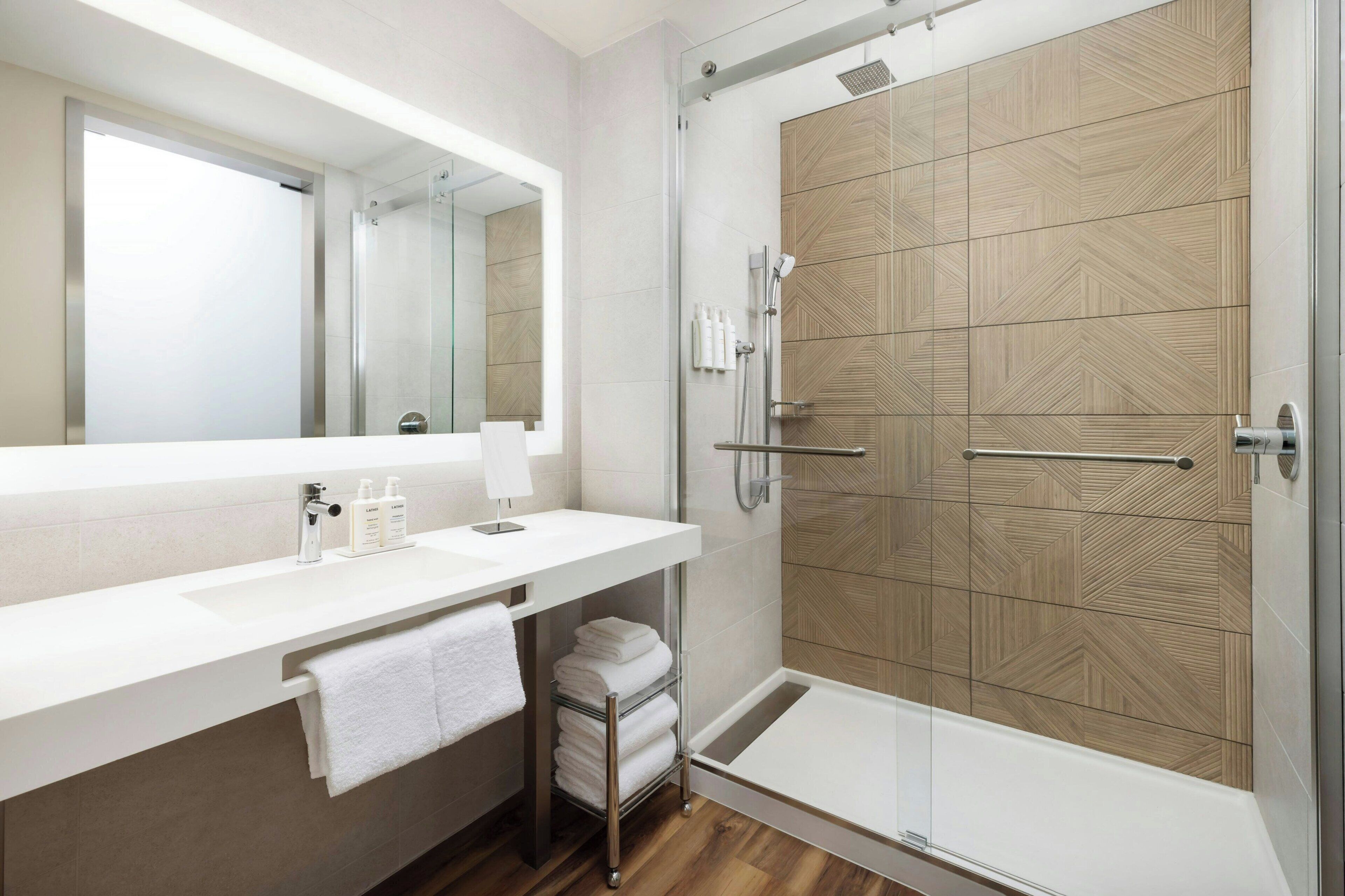 Un baño moderno con un espejo grande, un lavabo blanco y una zona de ducha.