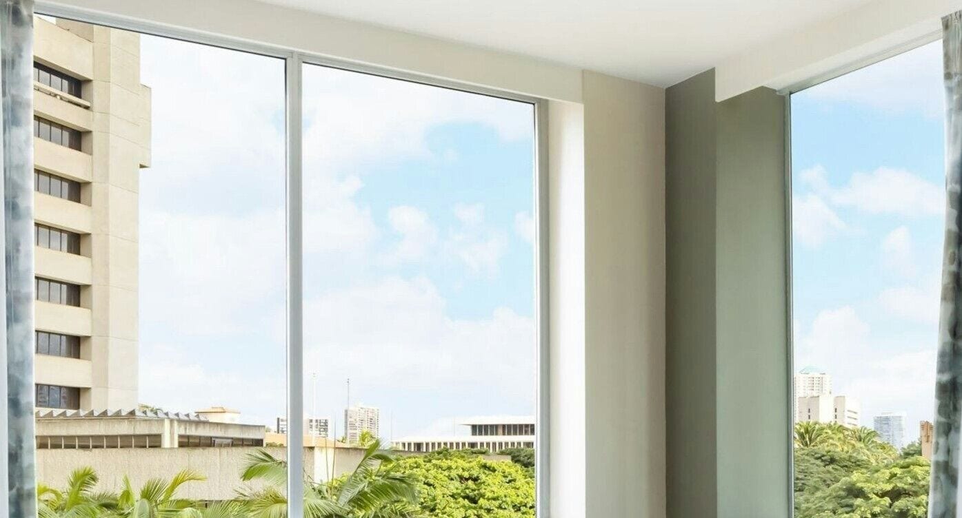 A room with large windows, a view of a cityscape, and a building in the background.