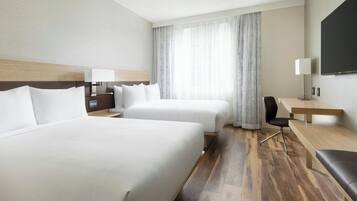 Habitación de hotel con dos camas, un escritorio, una silla y un televisor.