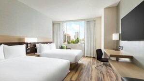 A hotel room with two beds, a desk, a chair, a TV, and a large window with a city view. - AC Hotel by Marriott Honolulu (Honolulu)