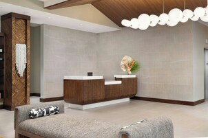 Un mostrador de recepción de diseño moderno, una zona de estar con cojines estampados y un abanico decorativo en la pared.