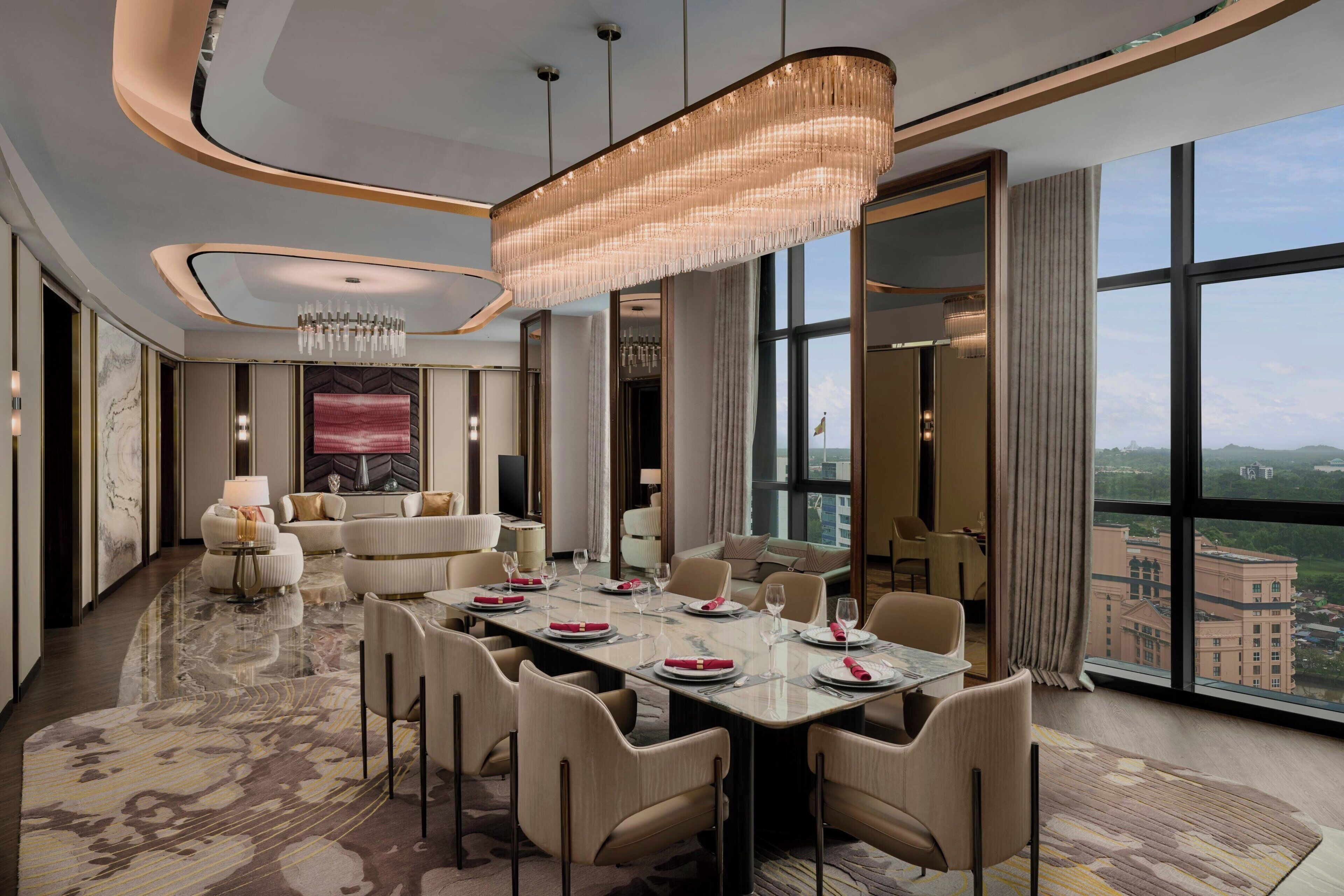 A modern hotel room with a dining area, large windows, and a view of the city.