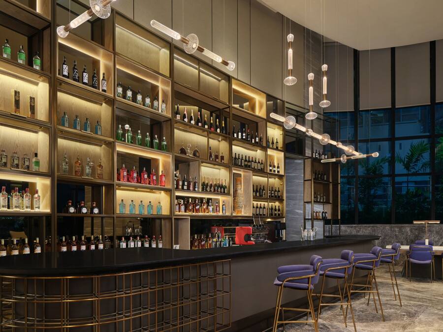 Eine moderne Bar mit Regalen voller Spirituosenflaschen, einer Theke und Sitzgelegenheiten.