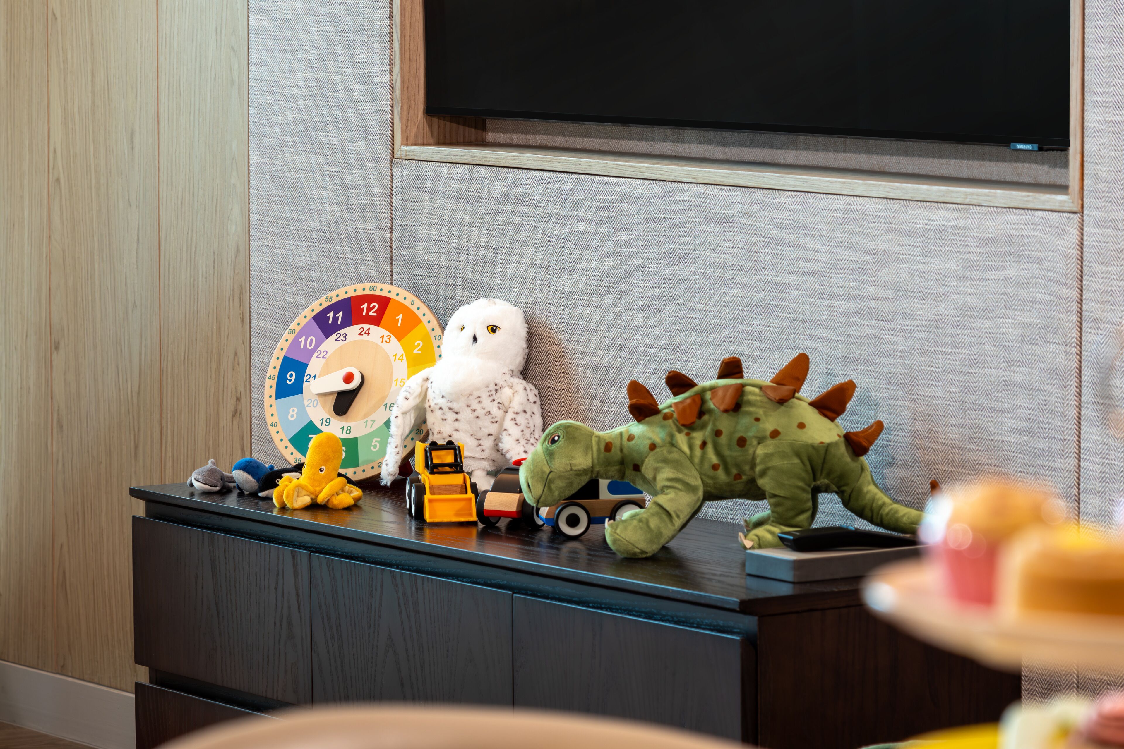 A wooden cabinet with toys and a clock.