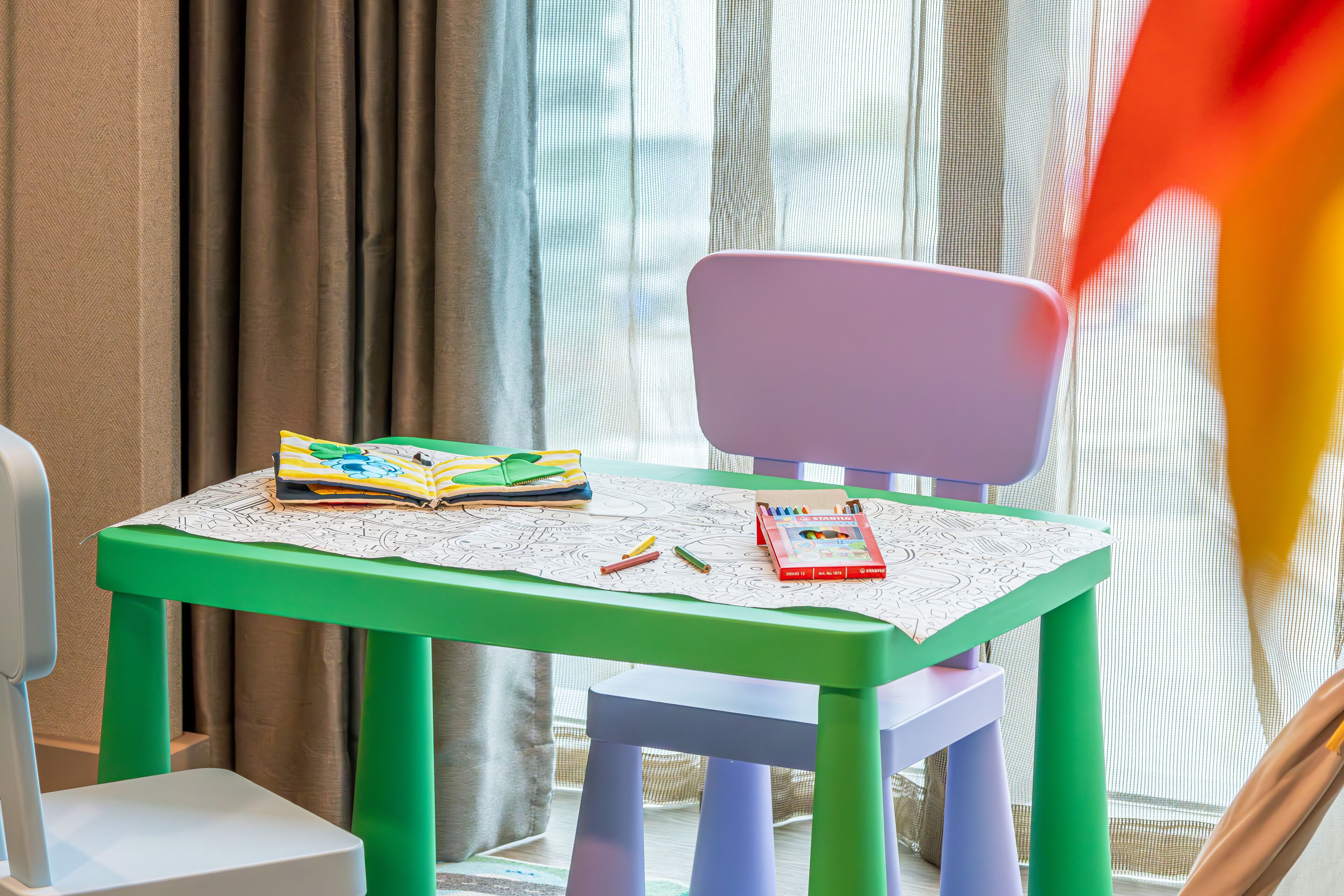 Una mesa infantil con un libro, crayones y un juguete.