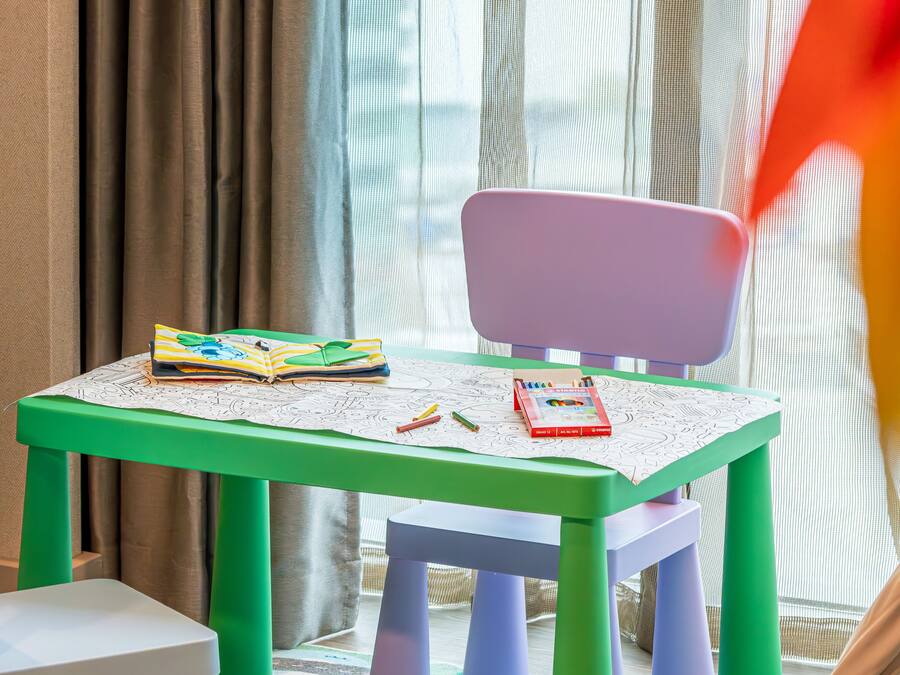 A child's table with a book, crayons, and a toy.