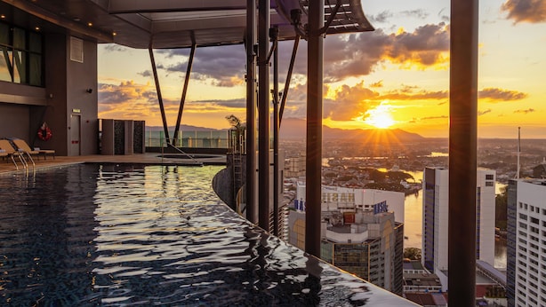 An infinity pool with a city view, modern architecture, and a sunset. - Sheraton Kuching Hotel (Kuching)
