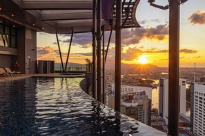 An infinity pool with a city view, modern architecture, and a sunset. - Sheraton Kuching Hotel (Kuching)