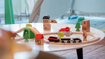 A wooden toy train set on a table with a house, a stop sign, and a bus.