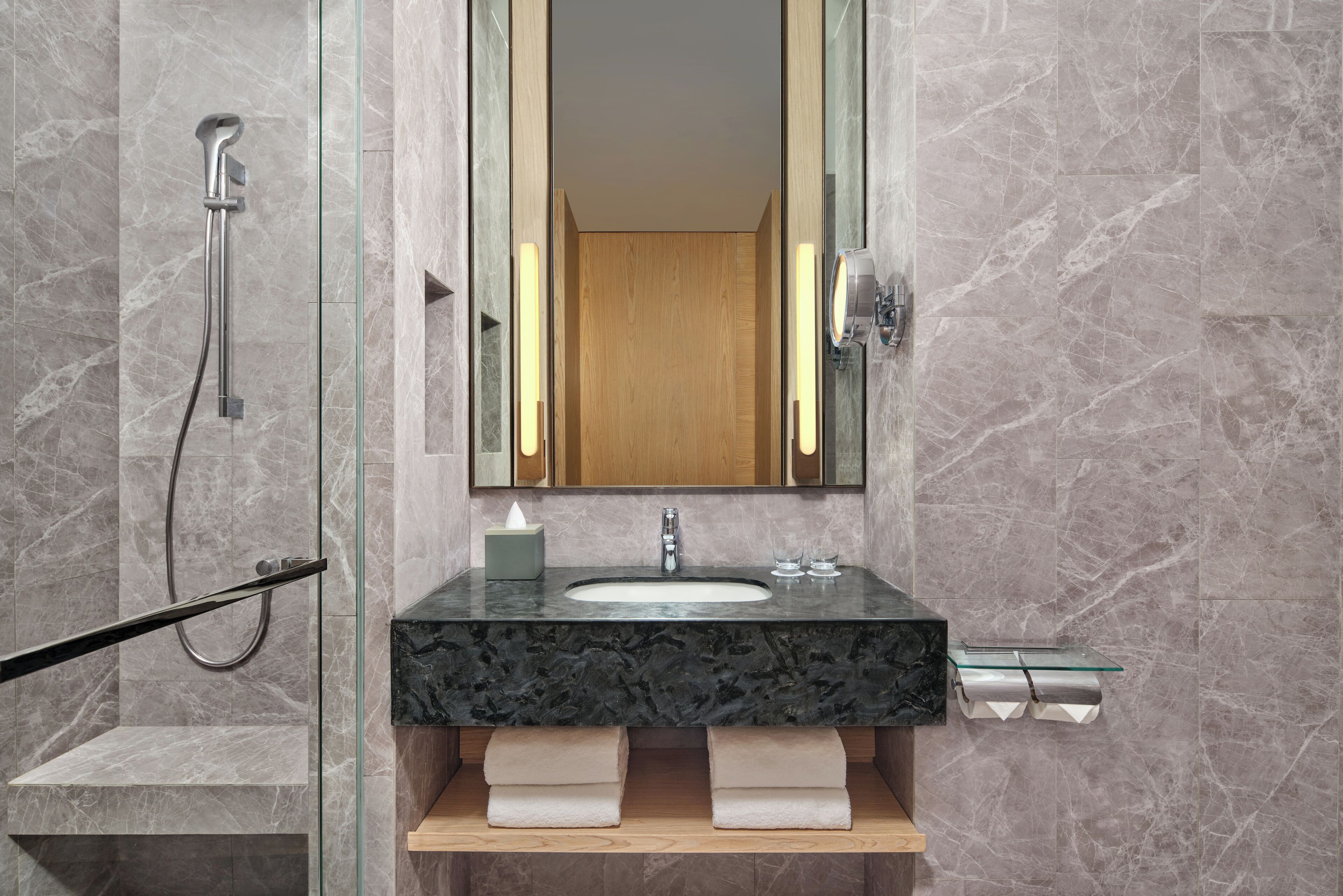 Une salle de bain moderne avec un lavabo en marbre, une cabine de douche en verre et un meuble-lavabo en bois.