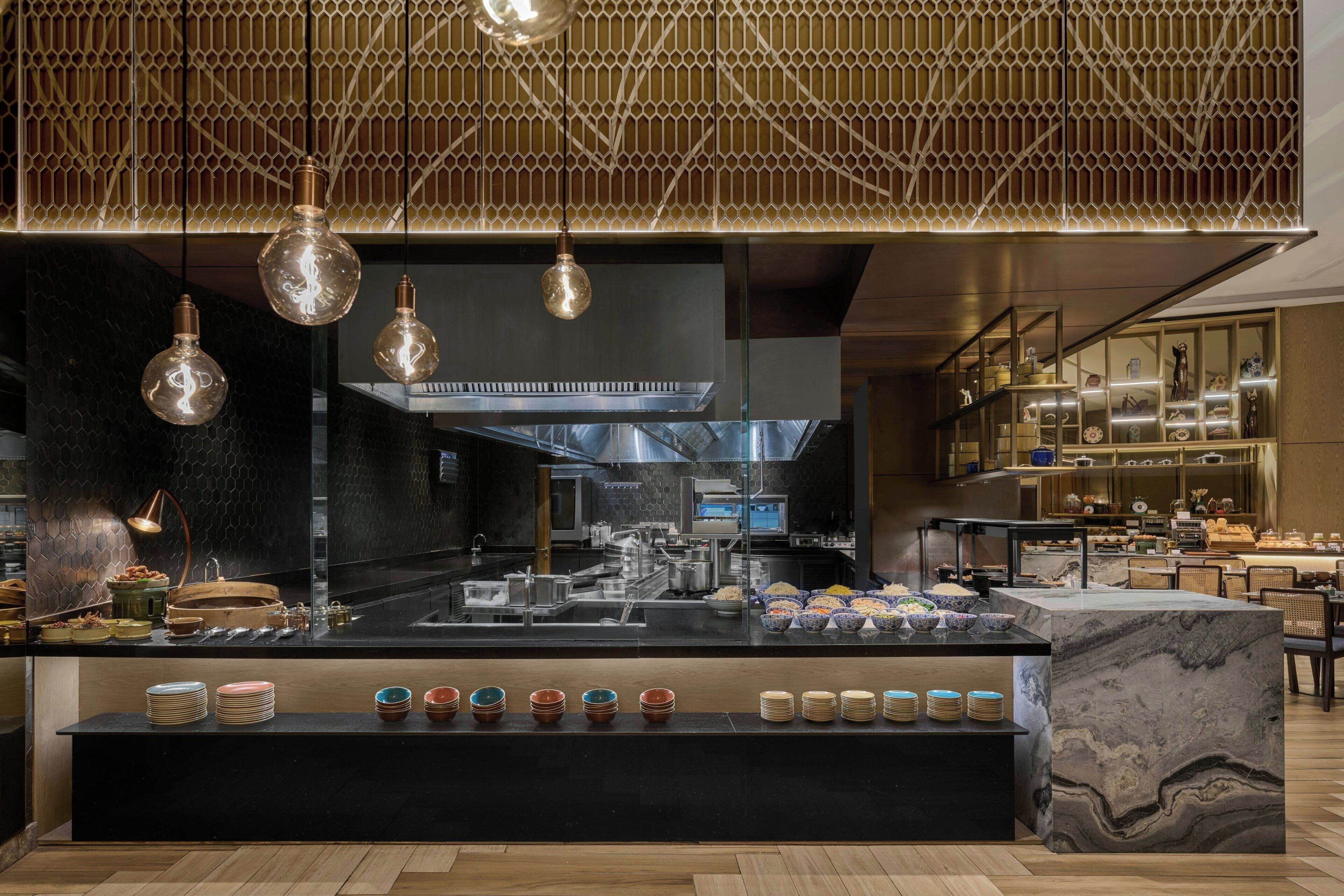 A modern kitchen with a central island, overhead lighting, and a variety of kitchenware.