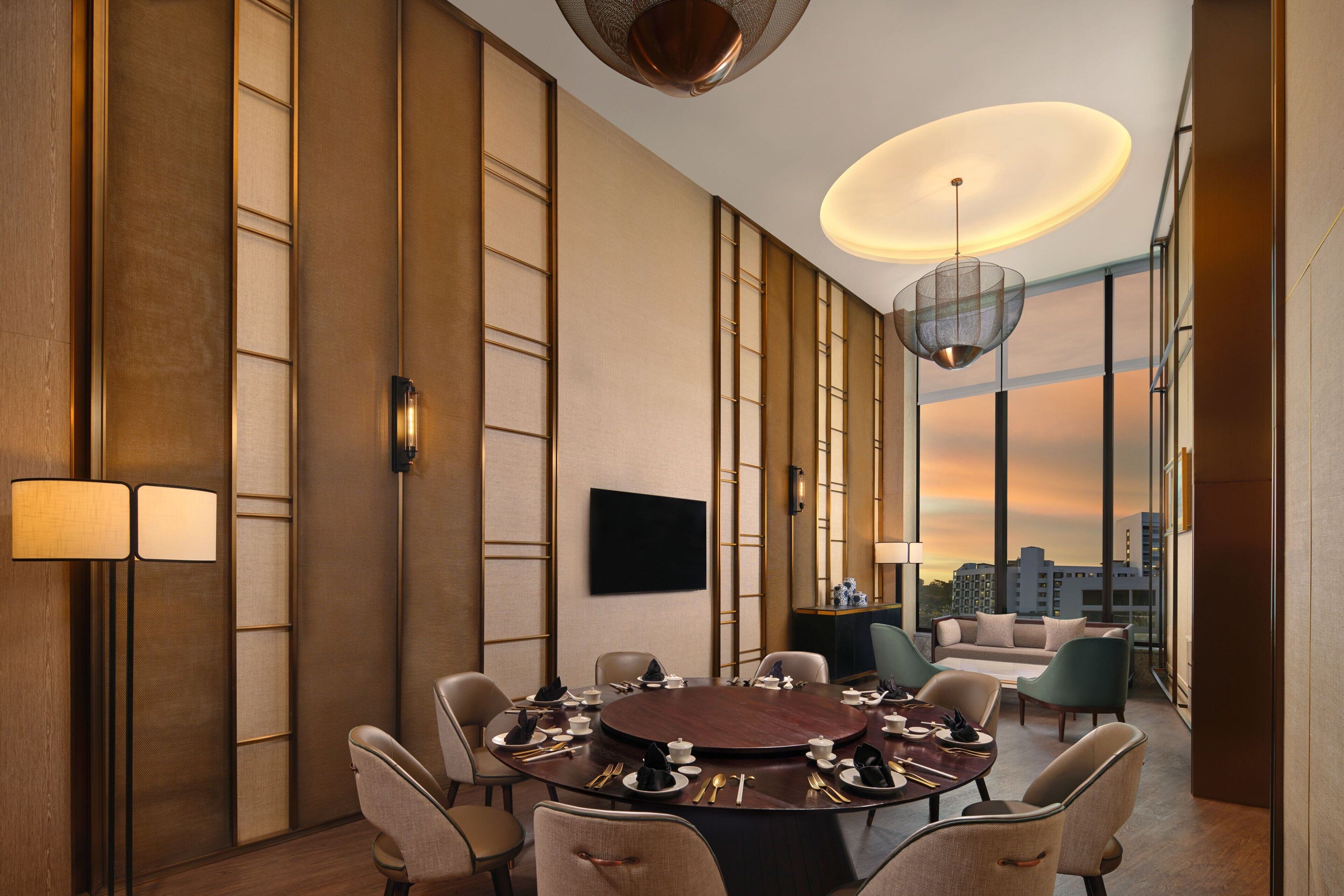 A modern conference room with a round table, chairs, and a city view.