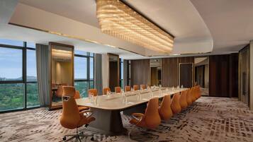 A conference room with a long table, orange chairs, and a large chandelier.