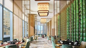 A modern hotel lobby with a marble floor, green chairs, a long table with chairs, and a wall of green vases. - Sheraton Kuching Hotel (Kuching)