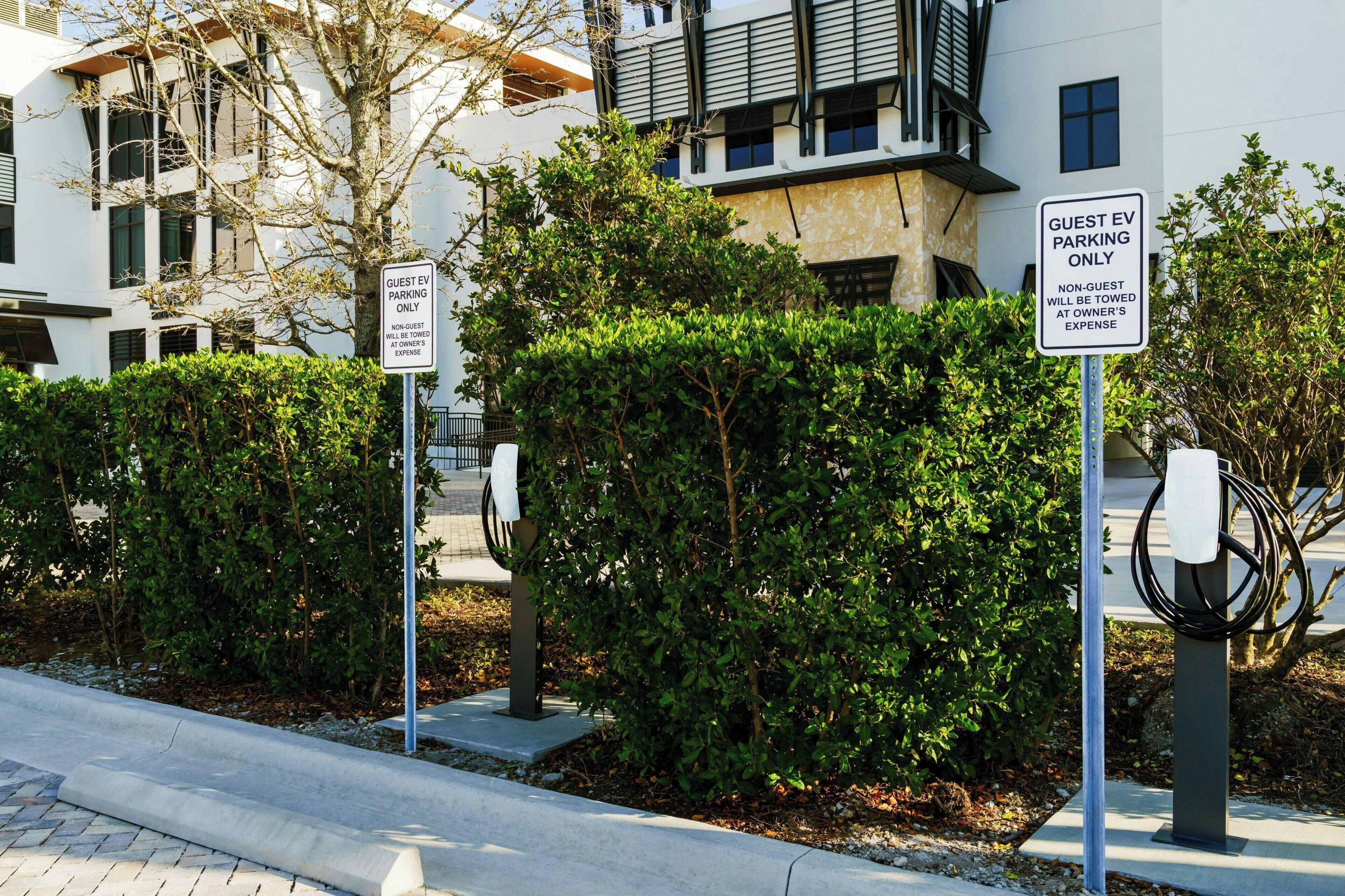 A modern building with guest EV parking signs and a charging station.