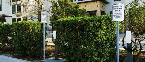 A modern building with guest EV parking signs and a charging station.