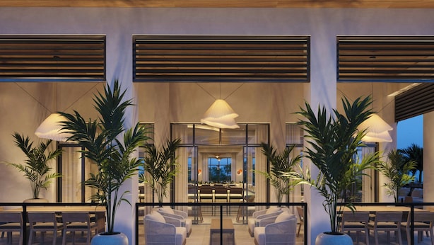 Un hall d’hôtel moderne comprenant un espace repas, des coins salon et de grands pots de plantes.