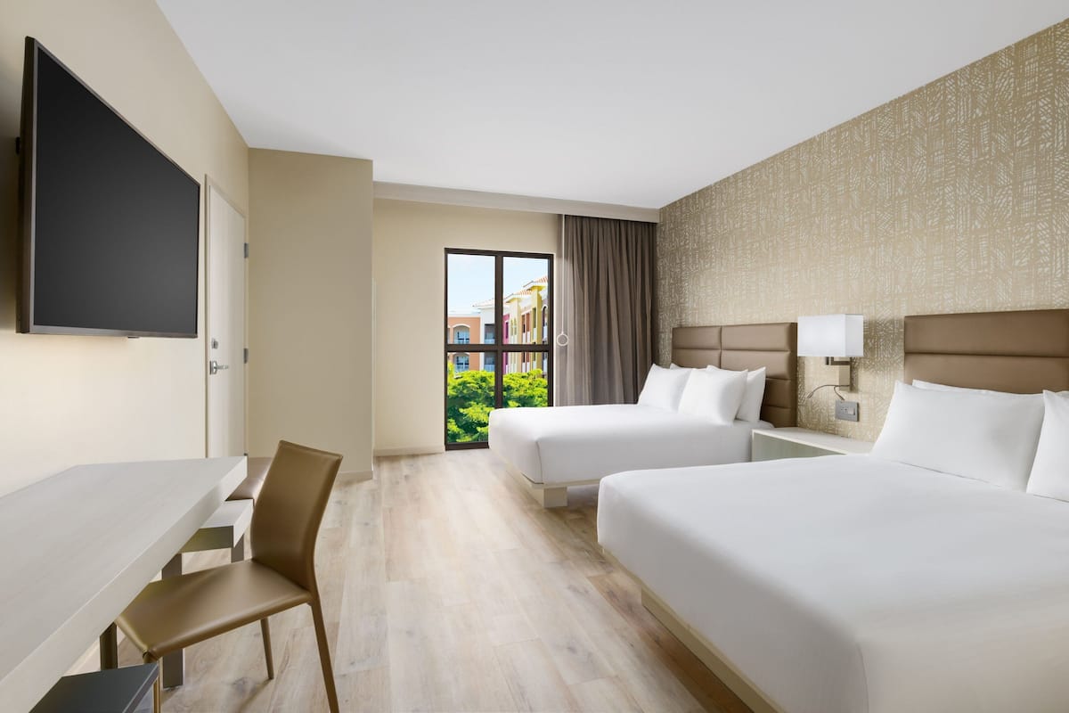 Une chambre d’hôtel avec deux lits, un bureau et une chaise.