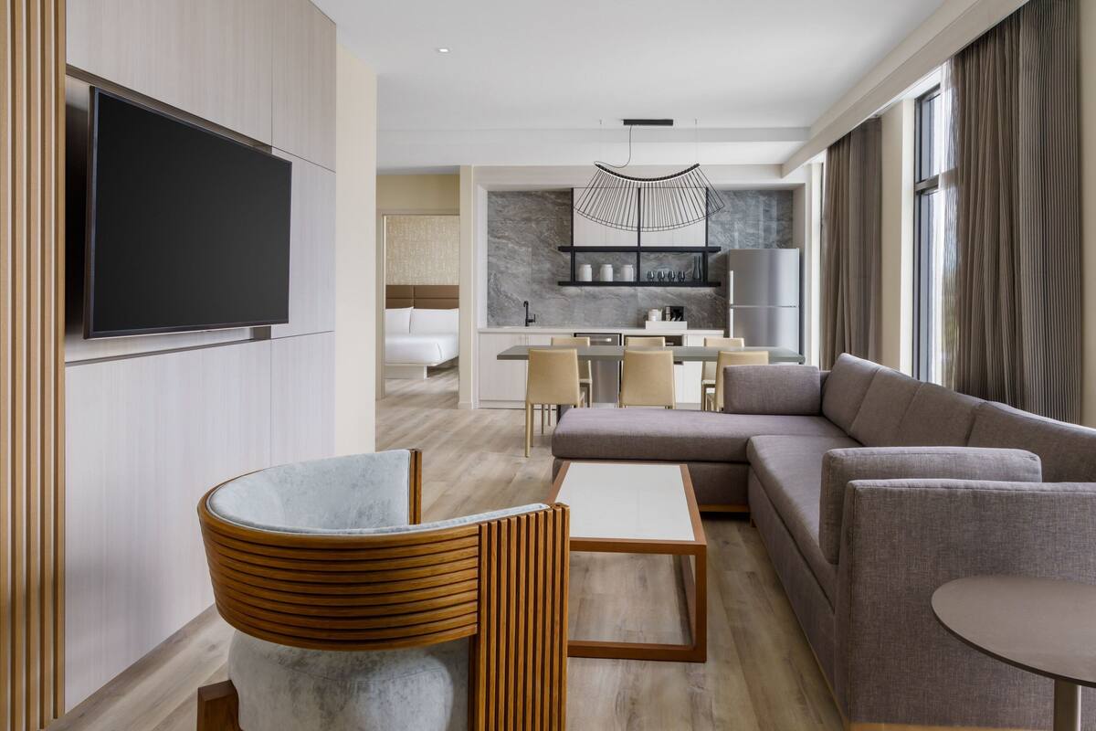 Une chambre d’hôtel moderne comprenant un espace salon, un coin repas et une cuisine.