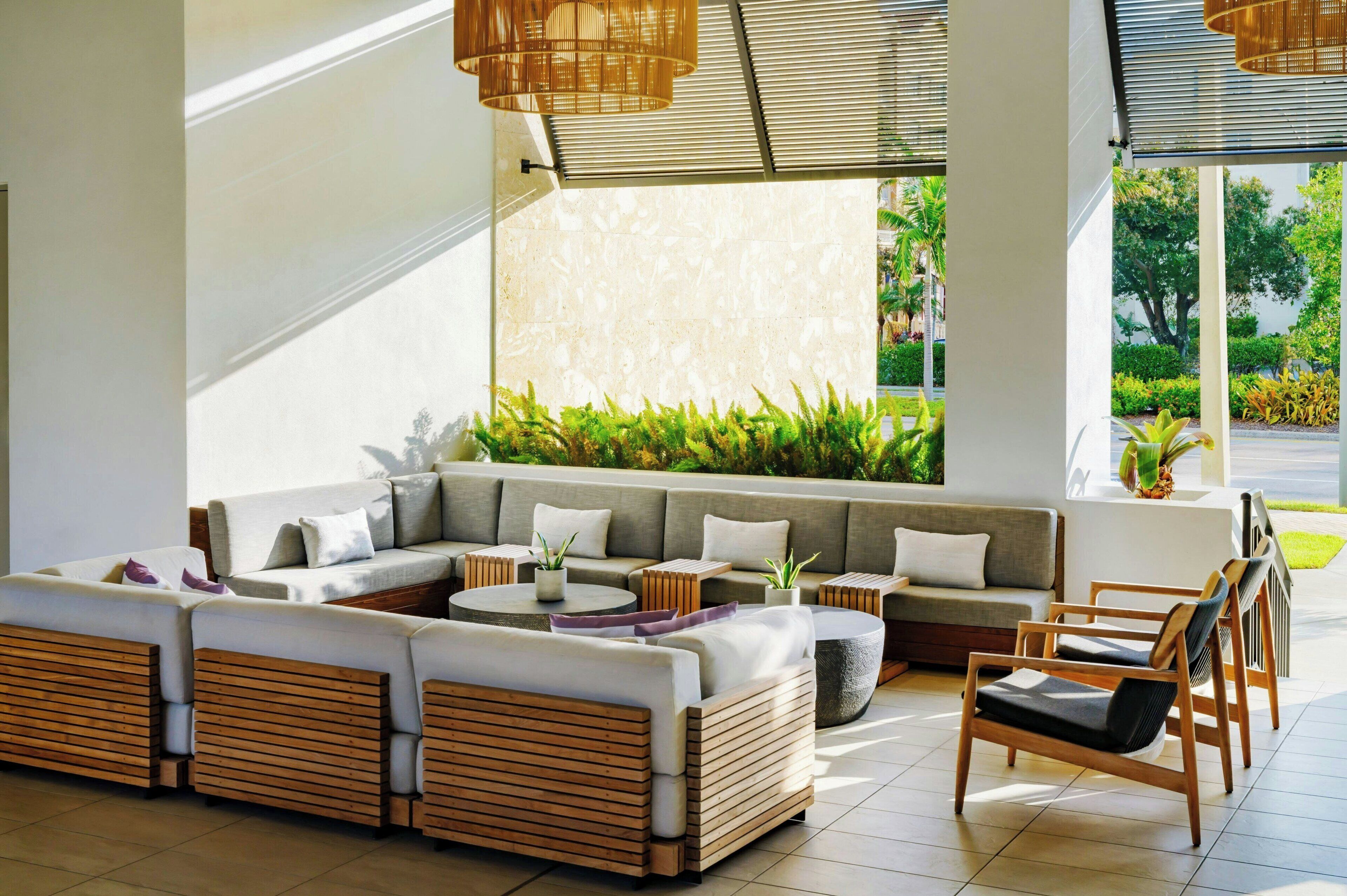 A modern outdoor seating area with a sectional sofa, round tables, and wooden chairs.