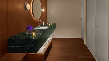 A modern bathroom with a marble sink, wooden paneling, a large mirror, and a wooden floor.