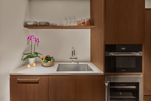 A modern kitchen with a built-in sink, a Miele oven, and a microwave.