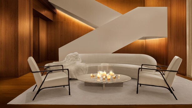 Un interior moderno con un sofá blanco, dos sillones y una mesa de centro redonda con velas.