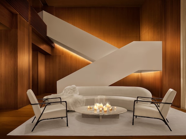 A modern interior with a white sofa, two armchairs, and a round coffee table with candles.