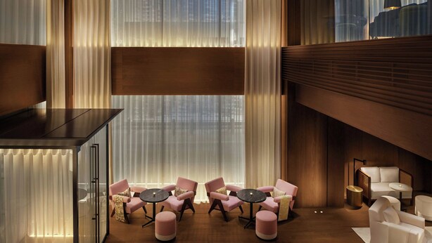 A modern hotel lobby with a wooden floor, a seating area with round tables and chairs, and large windows with sheer curtains. - The Tokyo EDITION, Ginza (Tokyo)