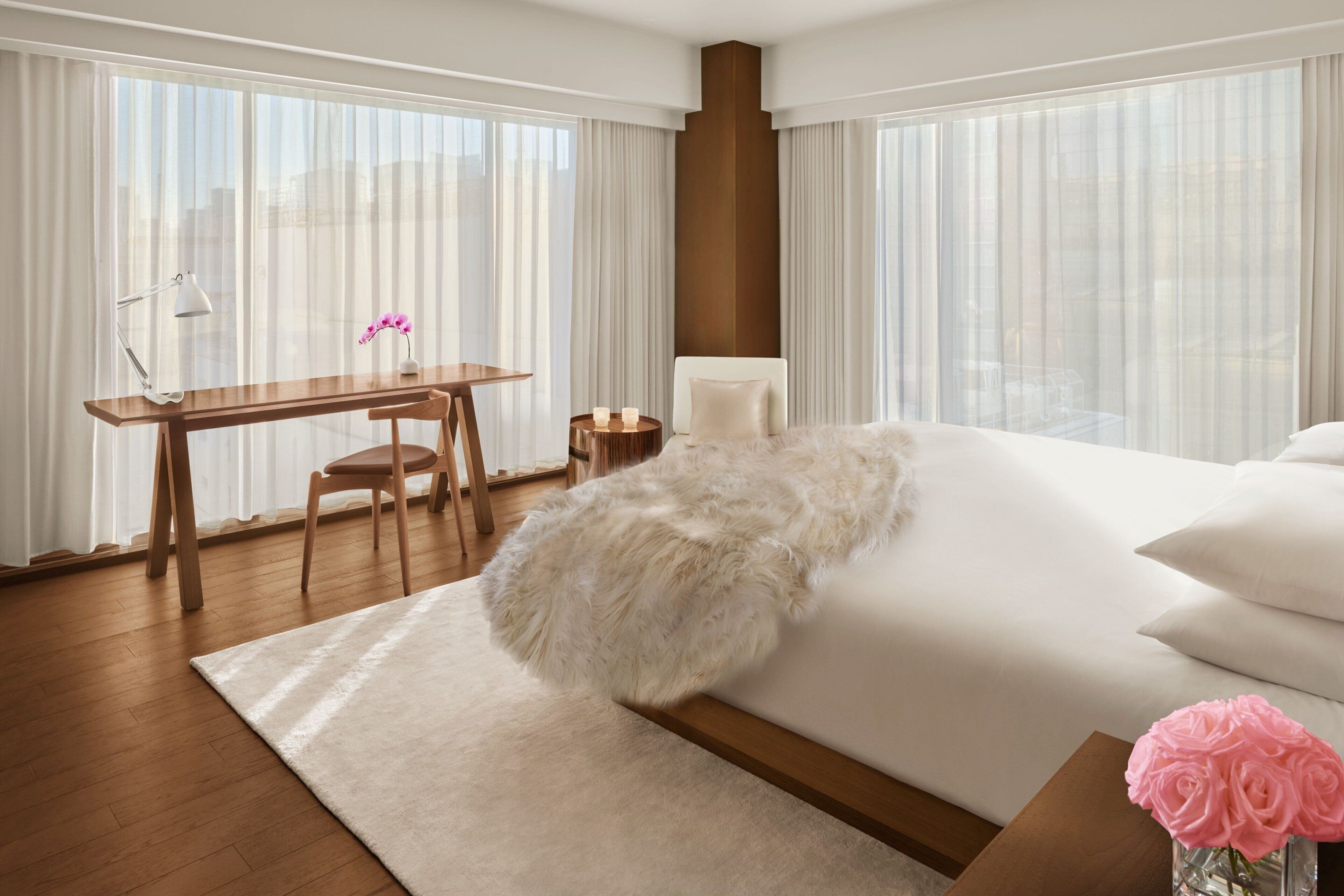 A modern hotel room with a large bed, a desk, and a chair.