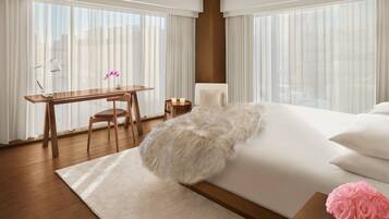 A modern hotel room with a large bed, a desk, and a chair.