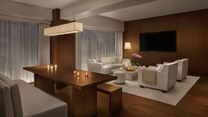 Una sala de estar moderna con una mesa de comedor de madera, sofás blancos y un televisor de pantalla plana montado en la pared.