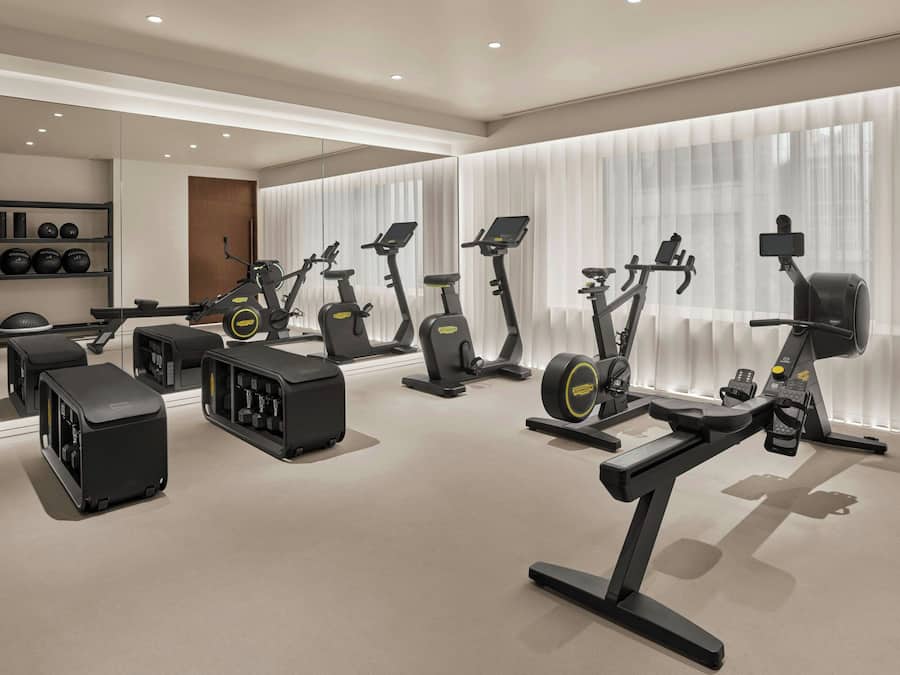 A modern gym with stationary bikes, treadmills, and weight machines.
