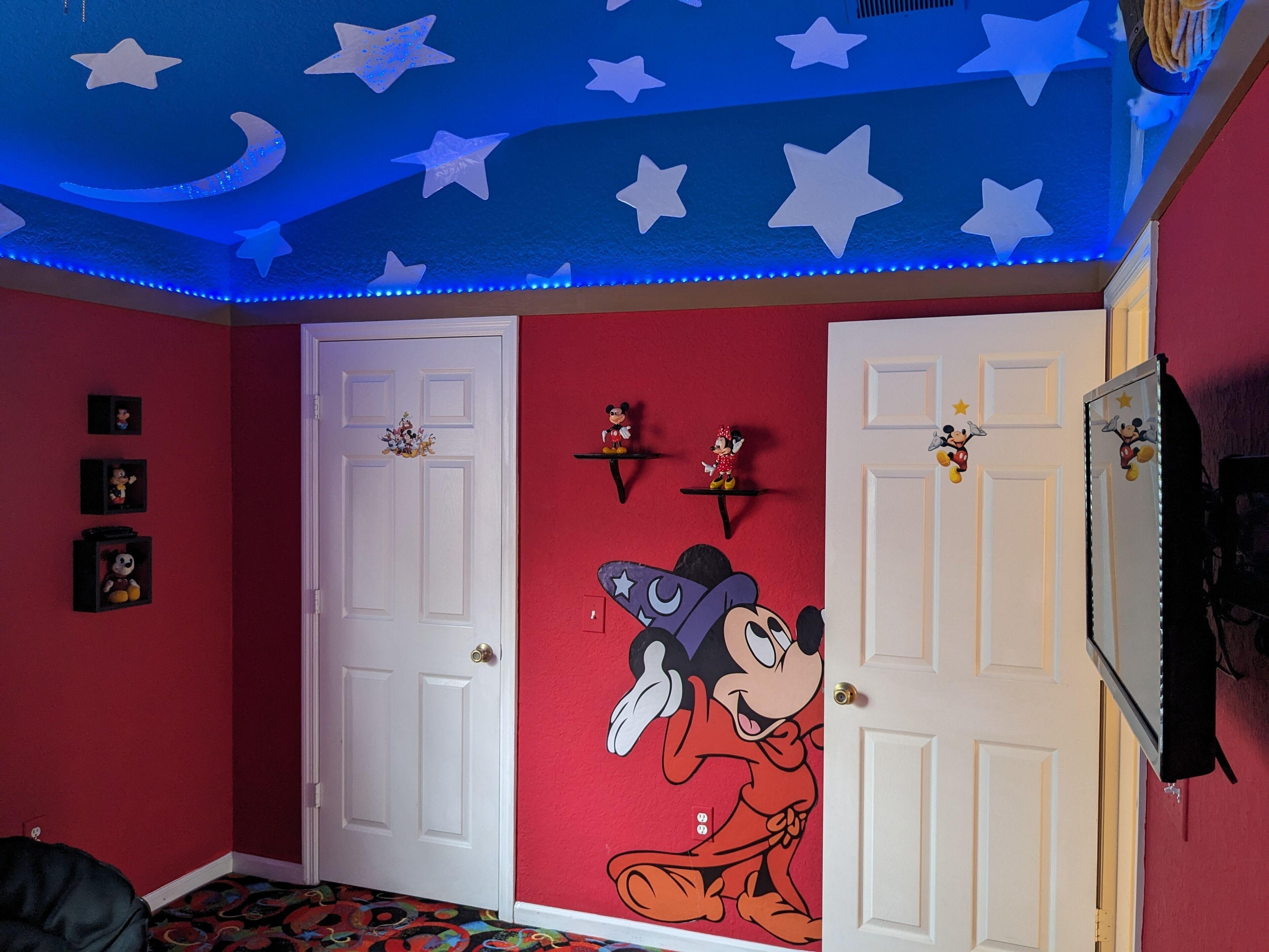 A room with a red wall, a white door, and a ceiling with star decorations.