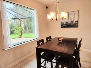 Enjoy meals with a garden view from this dining area featuring a large window, a dining table, and comfortable seating for six.