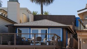 A beachfront property with a modern design, featuring a large patio area with outdoor seating and a staircase leading to a deck. - Oceanfront Cottage on the Sand at Miramar Beach (Santa Barbara)
