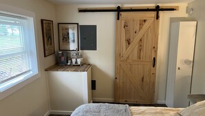 A bedroom with a bed, a coffee station, a sliding barn-style door, and a wardrobe.