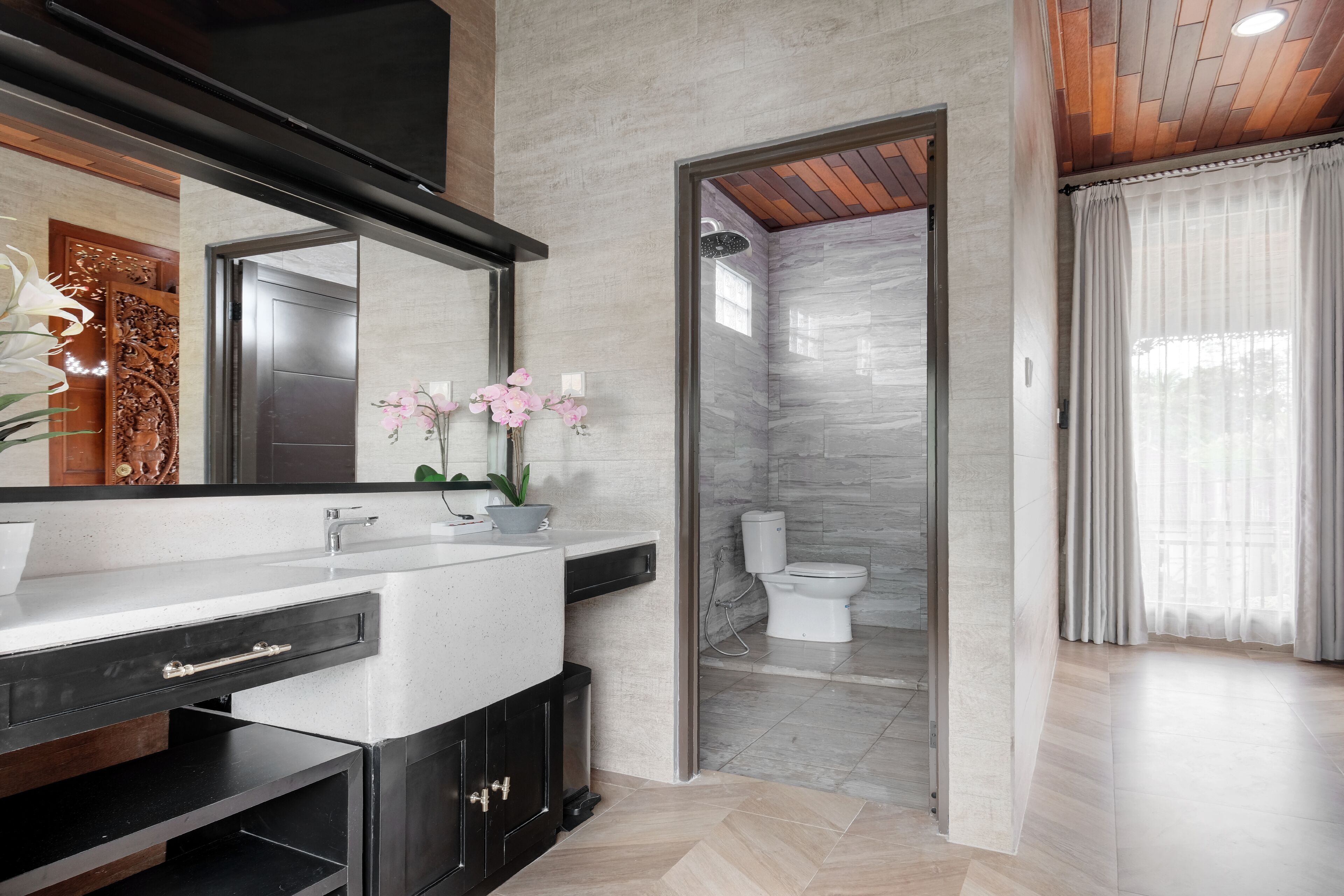 A modern bathroom with a marble sink, a large mirror, and a shower area with a glass door.