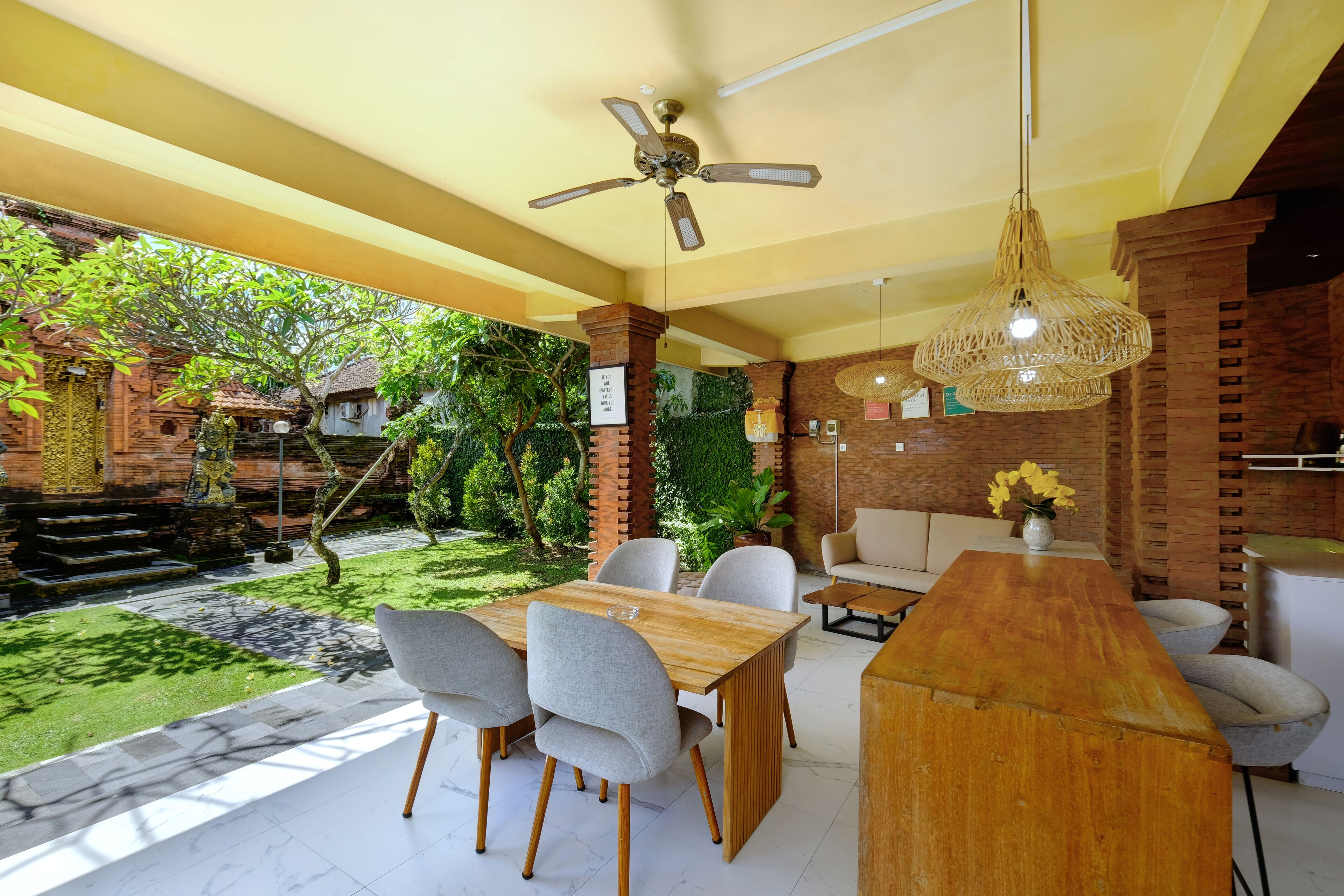 A modern dining area with a wooden table, grey upholstered chairs, and a ceiling fan.