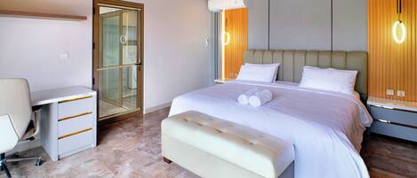 A modern bedroom with a bed, bedside tables, a desk, and an air conditioning unit.