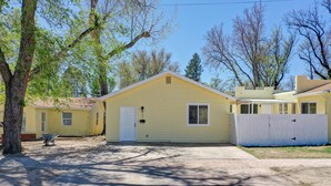 A single-story yellow house with a white door, a small porch, and a fenced yard. - Cozy 2/1 Pet Friendly/AC/Washer/Dryer/Off Street Parking near Downtown (Colorado Springs)